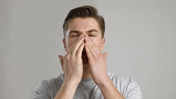 Close Up Portrait of Young Sick Man Rubbing His Sore Nose Grey Studio Background Slow Motion