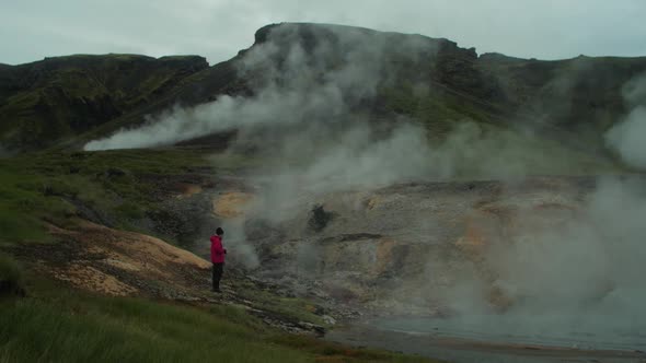 iceland landscape, geothermal hotspring steam smoke, distant figure of a one photographer taking a p