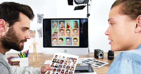 Two photographers having discussion over computer monitor