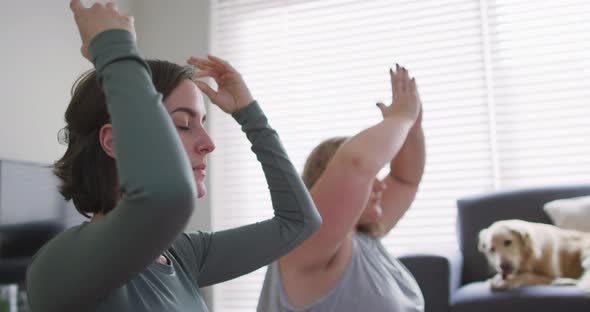 Caucasian lesbian couple keeping fit and meditating on yoga mat