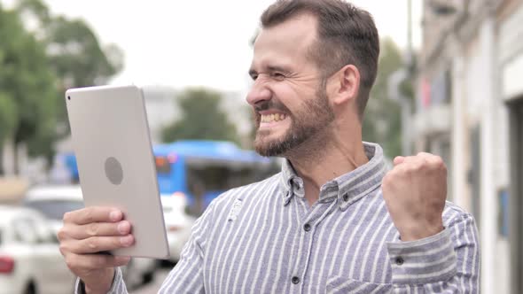 Man Cheering for Success on Tablet Outdoor