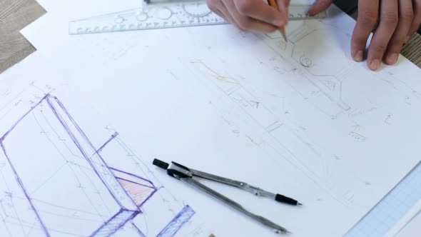 Architect working on a blueprint with a compass. Drawing tools. Creating a drawing.