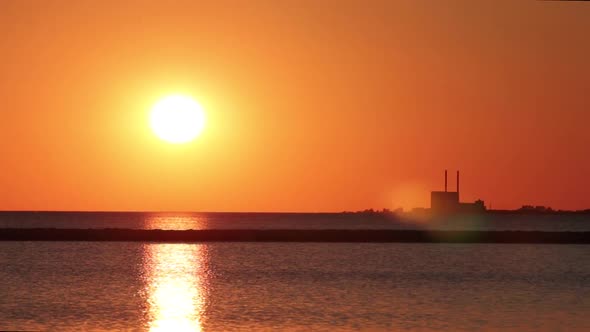 View of power plant at sunset, birds flying by