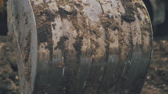 Excavator arm scoops up a bucket full of soil and rocks during roadworks in the countryside.