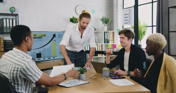 Manager Giving Papers to Multi Ethnic Team Members or Clients Presenting New Marketing plan