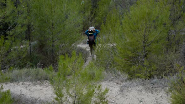 Wide Slomo From Behind of Girl Trekking in Green Conifer Forest Spain