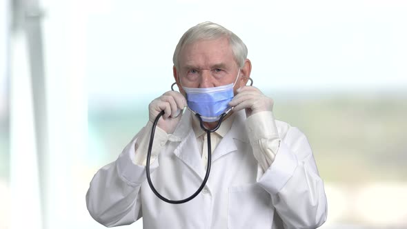 Old Senior Doctor in Mask Holding Stethoscope