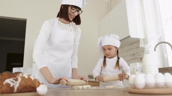 Close Up Mother Teaching Little Daughter to Work with Rolling Pin Standing at Table in Kitchen