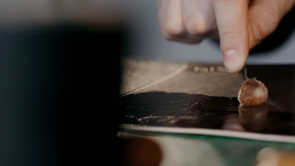 The Master Applies a Softening Cream To the Skin. The Process of Manufacturing a Travel Case Made of