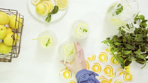 Fresh lemonade in a drinking glasses garnished with sliced of lemon and mint.