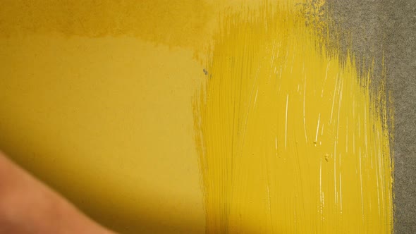 Painting Walls with Yellow Paint Using Brush Closeup