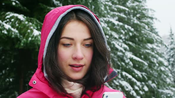 Smiling woman in warm clothing using mobile phone