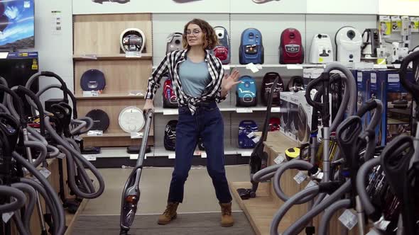 Funny Caucasian Woman in Casual Standing in Home Appliance Store Dancing Having Fun with Hand Helded