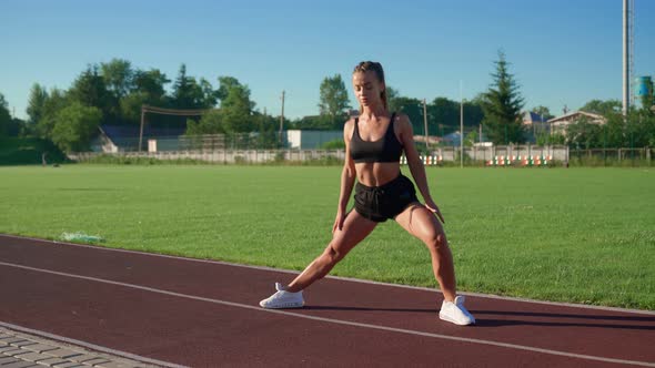 Young Woman Practicing Side Lunges at Stadium