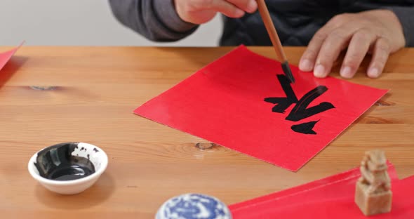 Man Write Chinese Calligraphy on Red Paper for Lunar New Year