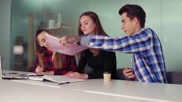 Three Students Working on Their Homework Sitting Together at the Table and Drinking Coffee