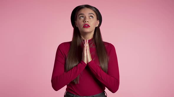 Attractive woman with long hair praying over red background. Pretty girl begging someone