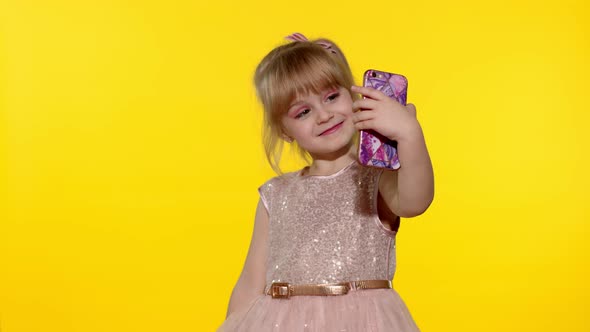 Child Girl Using Smartphone. Portrait of Blonde Kid Emotionally Makes Selfie on Mobile Phone