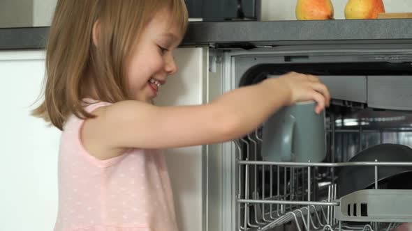 Little Girl Puts Cup in Dishwasher Smiles and Laughs