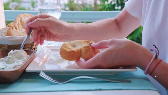 Woman eating bread with Greek dip Tzatziki in a restaurant.