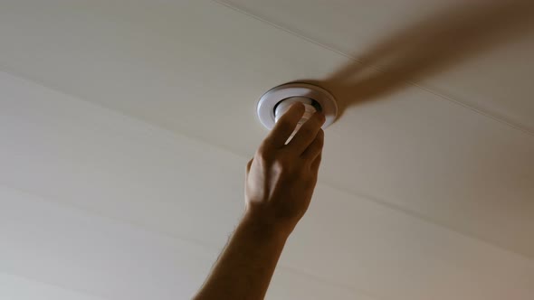 Male Hand Puts the Light Bulb in the Ceiling