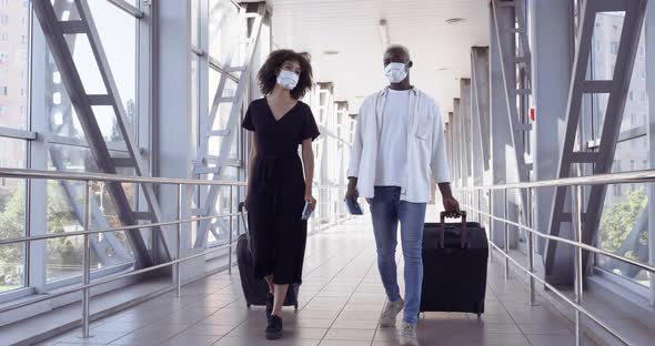 Ethnic African American Couple Wearing Protective Medical Masks and Carrying Suitcases Walks in