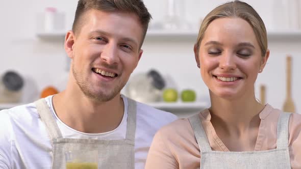 Healthy Family Couple Showing Glasses With Green Smoothies at Camera
