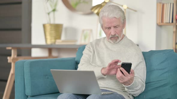 Old Man Working on Smartphone and Laptop on Sofa 