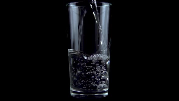 Water Is Poured Into a Transparent Glass. Glass on a Black Background. Slow Motion