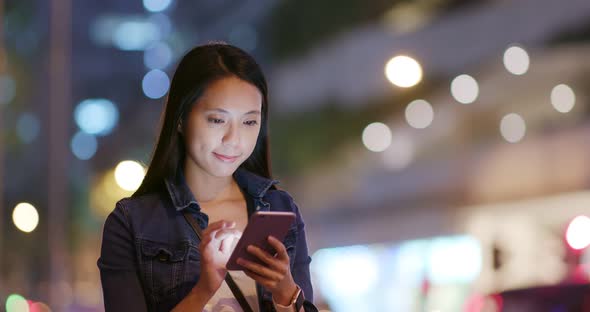 Woman use of smart phone in city at night