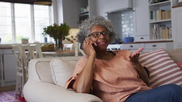 Senior african american woman talking on smartphone while sitting on the couch at home