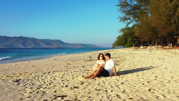 Young couple suntan on beautiful island beach vacation by blue lagoon with white sand background of 