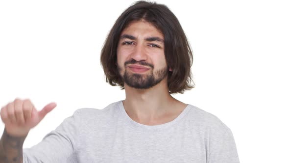 Longhaired Caucasian Guy Gesturing His Thumb Down Isolated Over White Background in Slowmotion