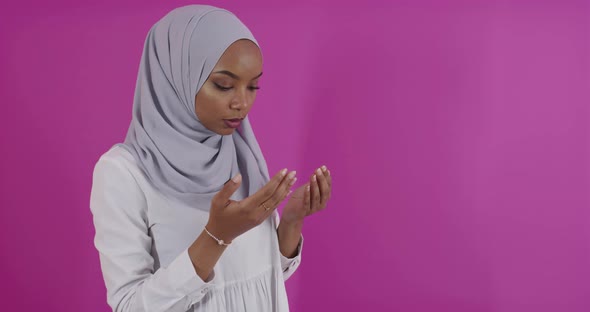 Modern African Muslim Woman Makes Traditional Prayer to God Over Colorfull Background