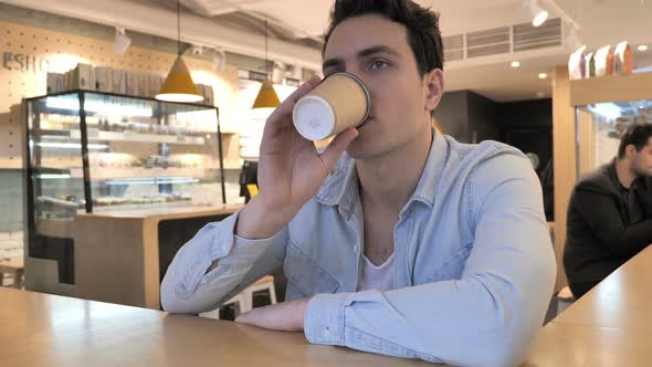 Young Man Drinking Coffee in Cafe