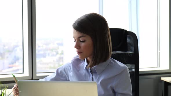 Beatiful businesswoman working on laptop writing notes in the office
