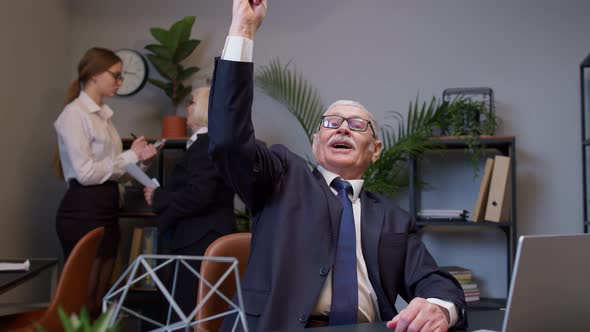 Thoughtful Business Man Using Laptop Sits at Office Desk Workplace Pointing Finger in Eureka Sign