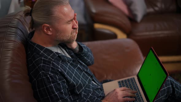 Busy Tired Man Messaging Online on Green Screen Laptop Closing Device Leaning on Couch in Home