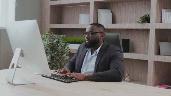 Concentrated African American Male Businessman Using and Typing on Computer During Working in Office