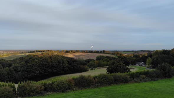 Wide aerial shot of a wind turbine in the countryside.