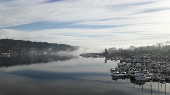 Thick fog slowly rolls into the mouth of Gig Harbor Washington, aerial dolly