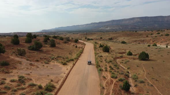 Four By Four Vehicle Driving Through Dusty Road At Daytime. - aerial follow