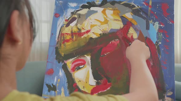 Close Up Of An Asian Artist Girl Holding Paintbrush And Painting A Girl's Face On The Canvas