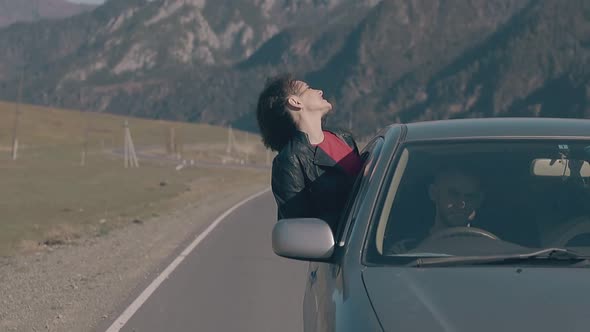 Lady with Dark Hair Leans Out of Speeding Car Window