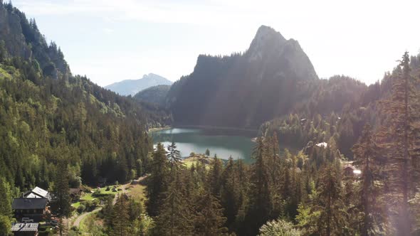 Flying low over treetops towards stunning lake and beautiful mountainside