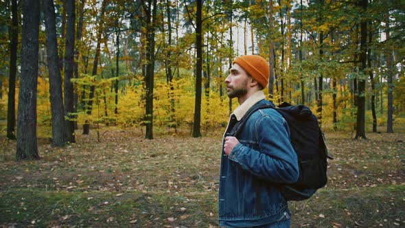 Young Man with Tourist Backpack Walking Alone Through Autumn Forest Wild Nature Enjoying Hiking