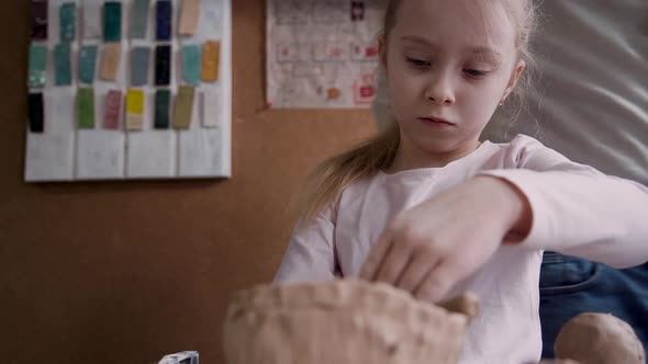 Calm Girl Molding Wet Clay in Craft Studio Room