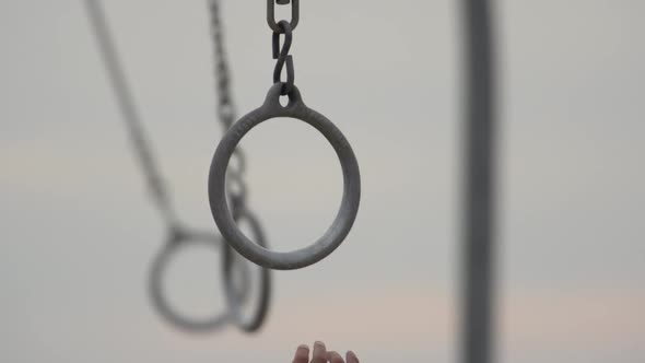 Individuals swinging on traveling rings on Santa Monica beach.