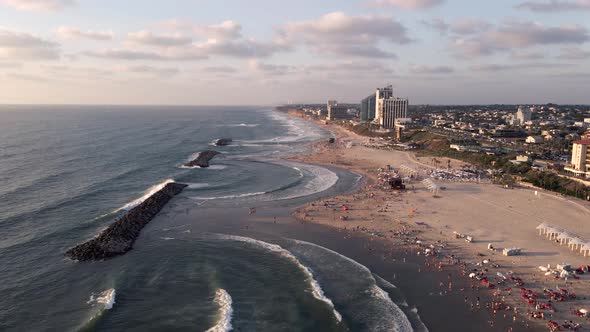 View of a beautiful tourist beach with sea and waves at sunset near the town of Herzelia in Israel