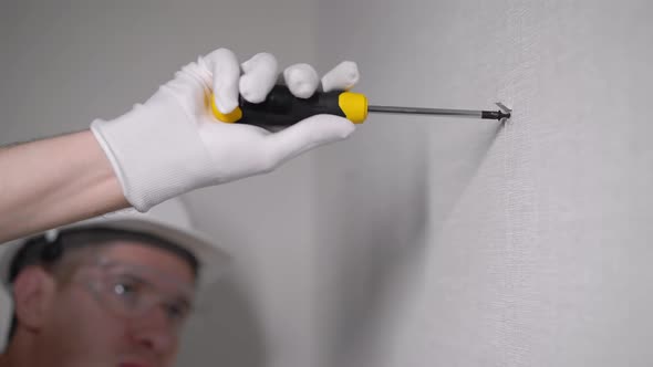 Builder Worker Makes Repairs in Apartment Screwing Screw in a Concrete Wall